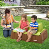 Mother attending to girl and boy sitting on 2 seat bench outdoors
