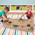 Two children playing monster trucks on the Carry and Go Track Table in a playroom