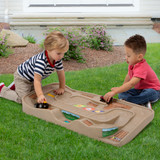 Two children playing monster trucks on the Carry and Go Track Table outside