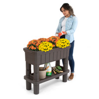 Woman standing to tend flowers in the Raised Patio Garden