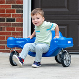 Toddler boy seated riding in the Simplay3 Galaxy Glider in a driveway